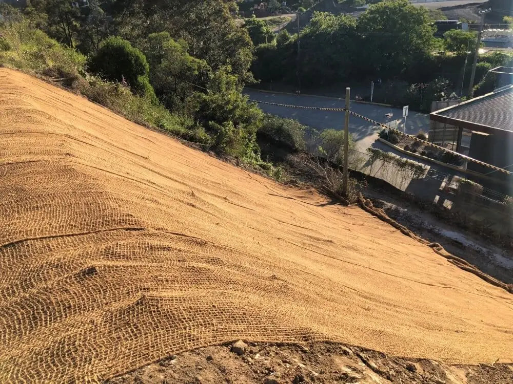 Coir mesh covering a hillside to prevent soil erosion in an outdoor landscaping project