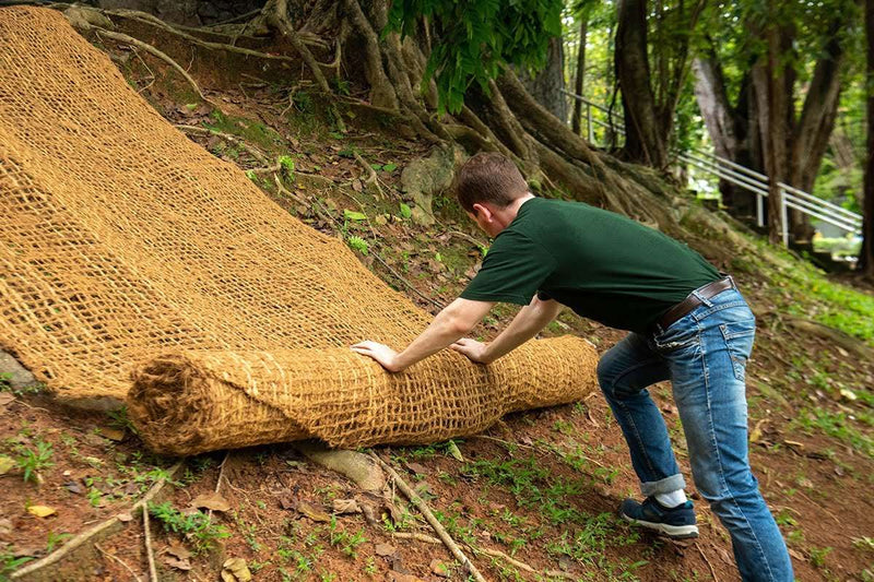 Person laying coir mesh on a slope