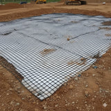 Composite biaxial geogrid with geotextile laid over a construction site for soil reinforcement