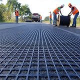 Workers installing HEIGER fibreglass geogrid on a road for improved ground stability