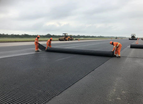 Workers installing HEIGER fibreglass geogrid on a runway for enhanced durability and stability
