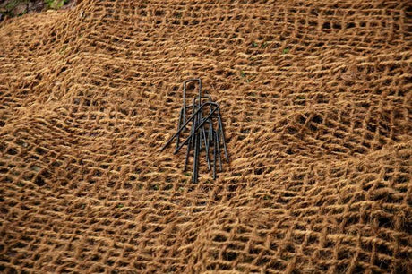 HEIGER black metal weed mat pins placed on brown natural fiber weed mat for garden use