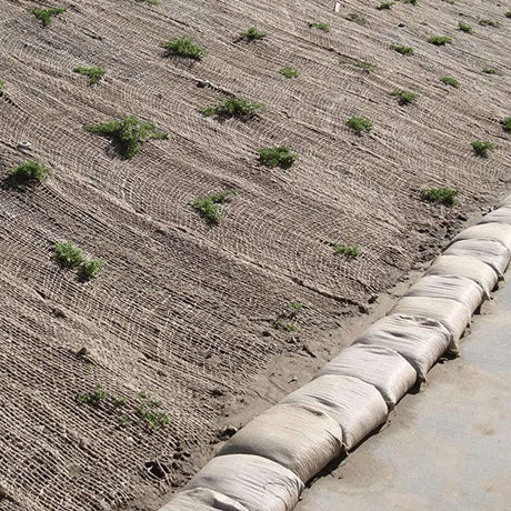 HEIGER jute mesh covering soil on a slope with sandbags along the edge for erosion control
