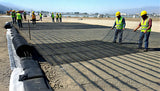 Construction workers installing PP uniaxial geogrid on a gravel surface for ground stabilization