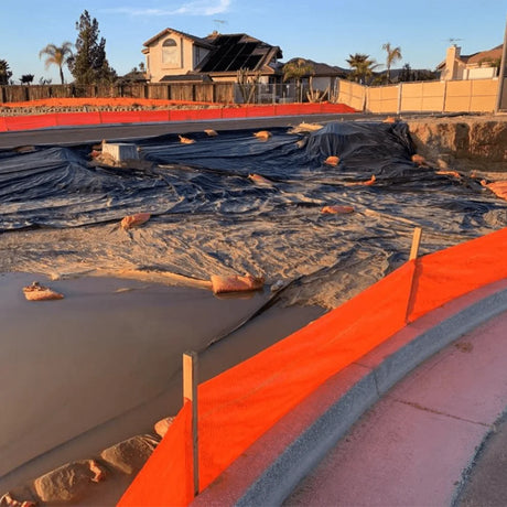 HEIGER bright orange silt fence installed around a muddy construction site for sediment control